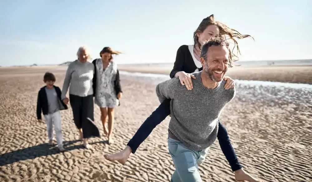 Happy father carrying daughter piggyback on the beach, spring break destinations