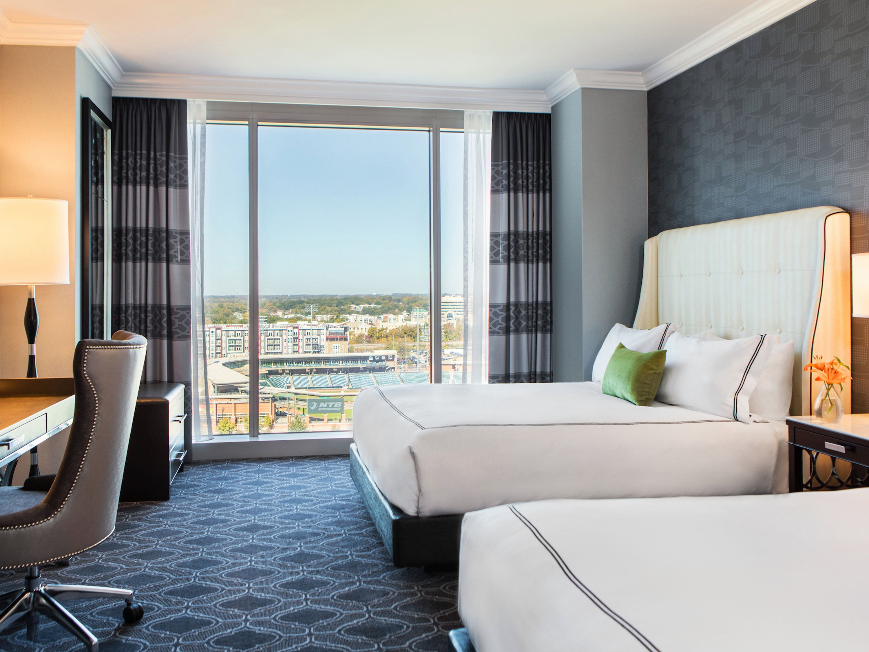 Two queen guest room at Kimpton Tryon Park Hotel with white bedding and floor-to-ceiling park-facing windows
