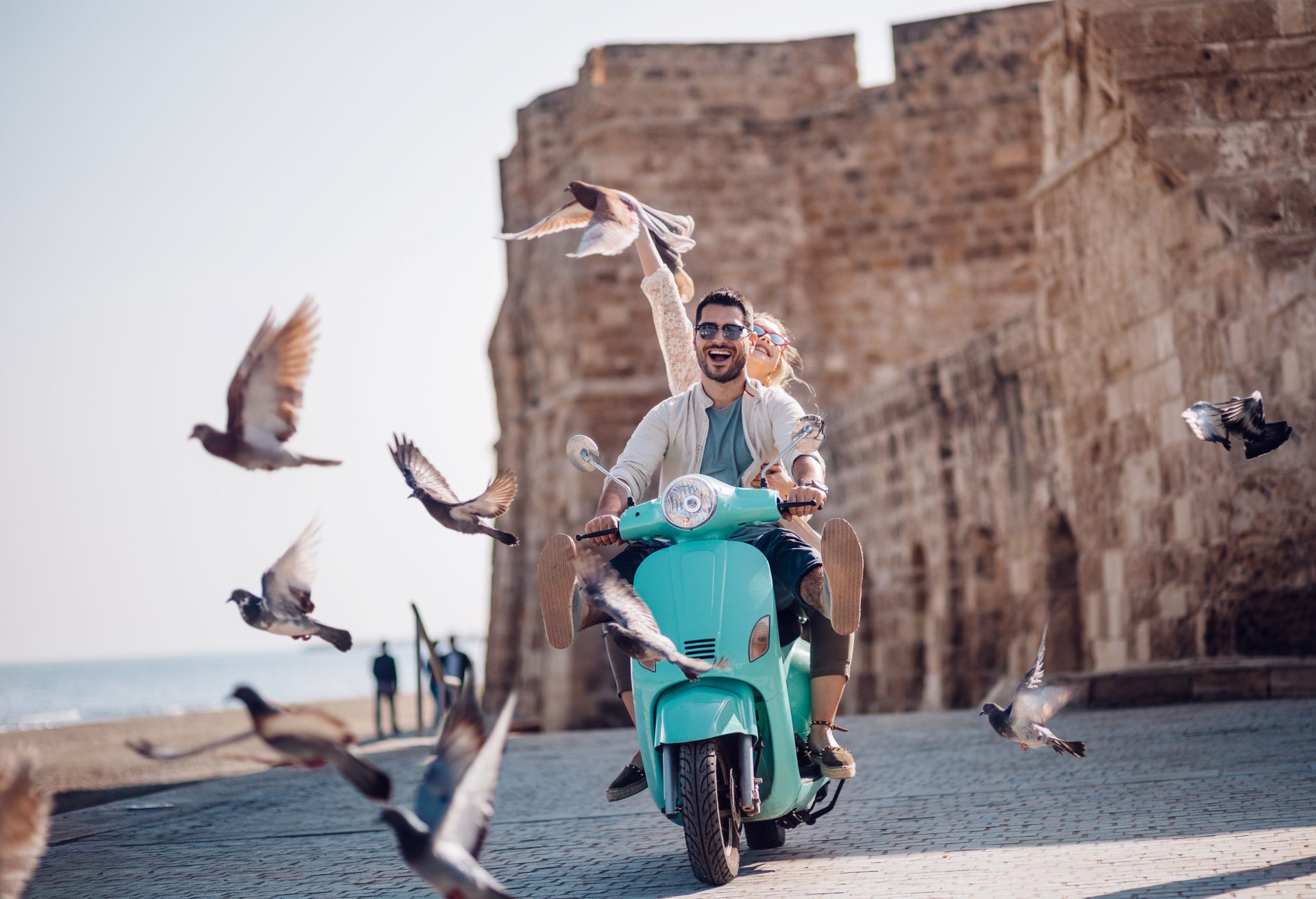 Young couple having fun riding scooter in old European town