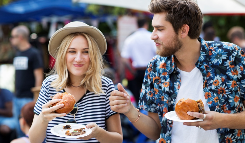 Couple eating burgers at food market