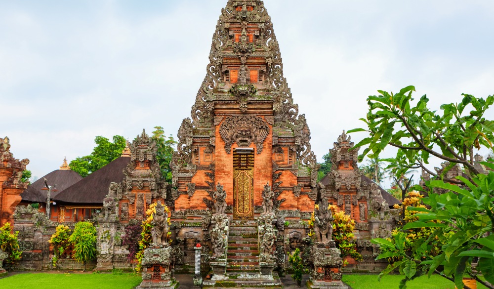 Details of traditional balinese hindu temple. Entrance gate with door, stone carving, Bhoma sprit face, guards sculptures. Popular travel destinations, art, culture festivals of Bali island, Indonesia