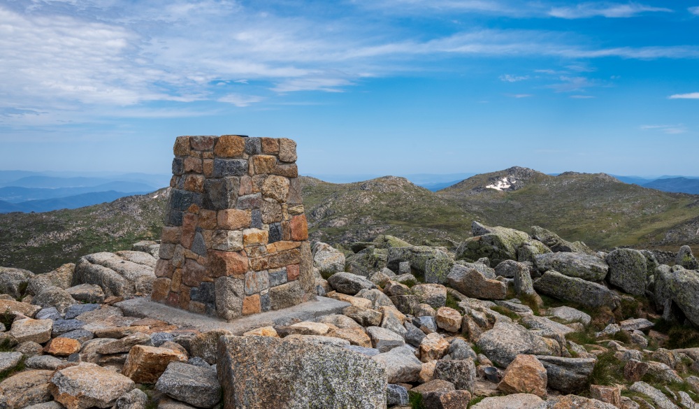 View from the top of Mount Kosciuszko, the tallest mountain in Australia at 2,228m. This photo was taken in Kosciuszko National Park in summer, located in the Thredbo-Perisher area in NSW Australia. The park is notable for hiking, wildflower viewing and mountain biking activities in summer, and snow sports and skiing in winter.