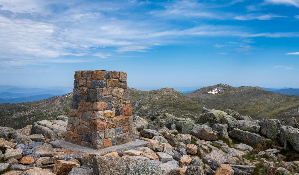 View from the top of Mount Kosciuszko, the tallest mountain in Australia at 2,228m. This photo was taken in Kosciuszko National Park in summer, located in the Thredbo-Perisher area in NSW Australia. The park is notable for hiking, wildflower viewing and mountain biking activities in summer, and snow sports and skiing in winter.