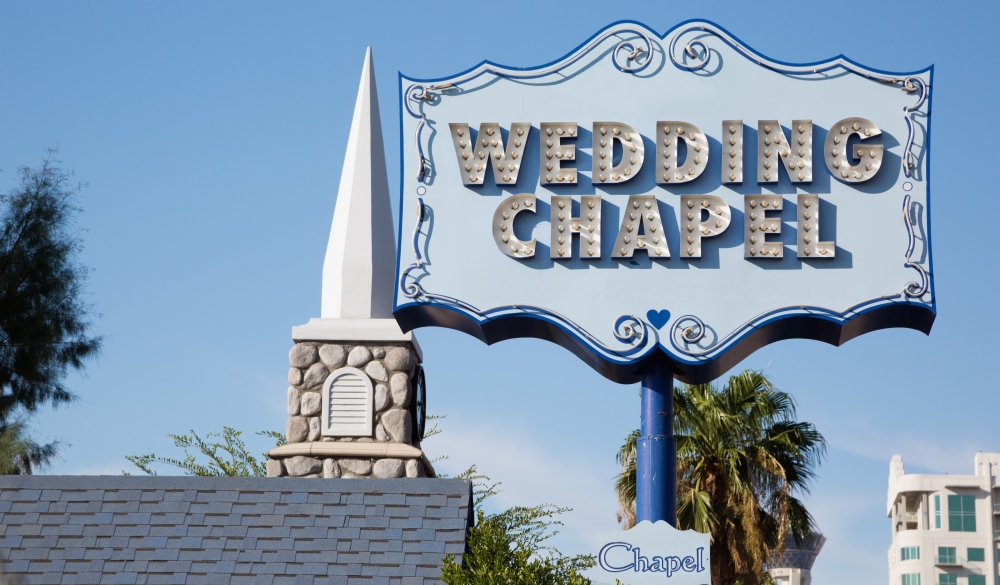 Wedding chapel sign in Las Vegas. In the background a false bell tower.