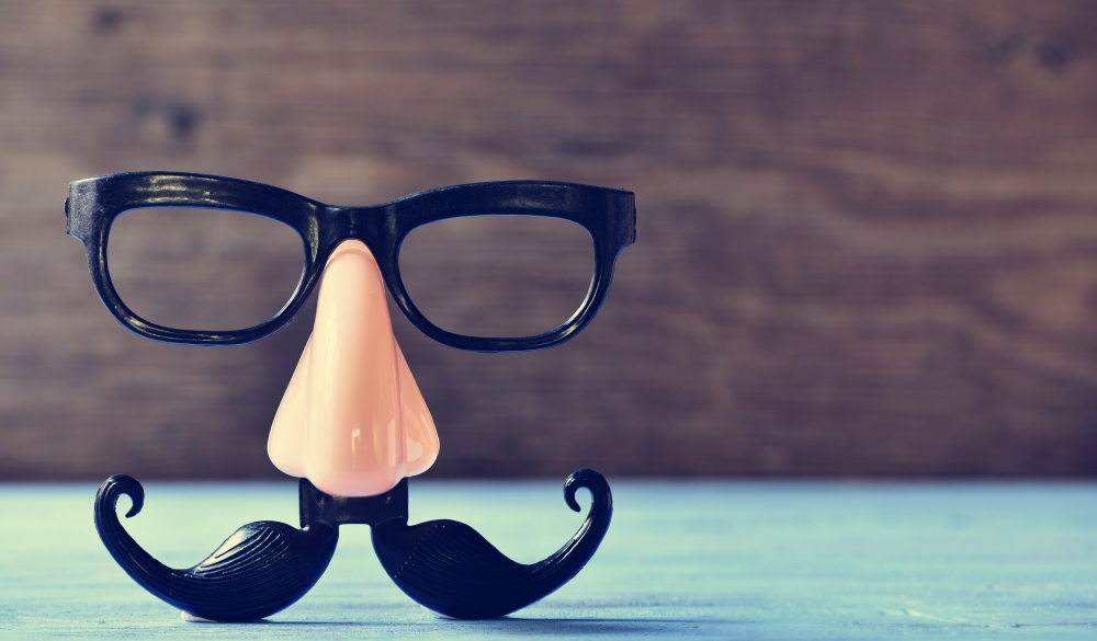 a fake mustache, nose and eyeglasses on a rustic blue wooden surface;