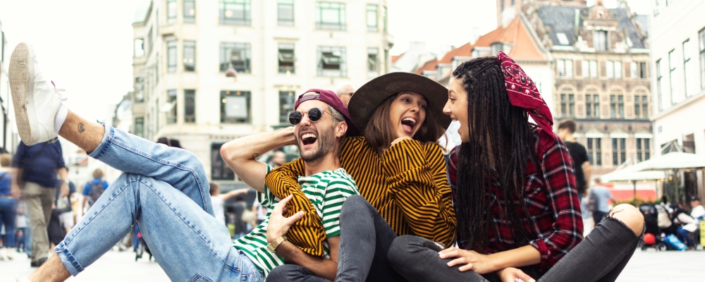 Happy three friends in Copenhagen sitting on the floor and laughing