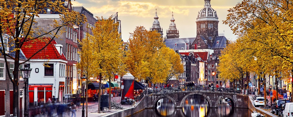 Autumn sunset in Red-light district. View at Church saint Nicholas above bridge canal with boats