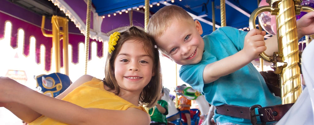 Two cute kids having fun while riding a carousel at an amusement park or carnival