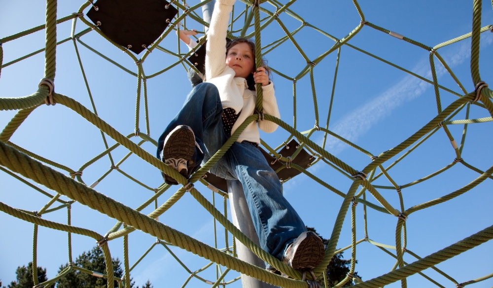 A girl climbing on a playground set with blue sky in the background; Shutterstock ID 36771469