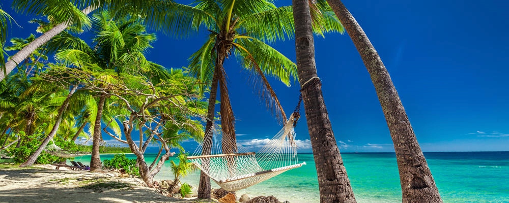 Empty hammock in the shade of palm trees on vibrant tropical Fiji Islands