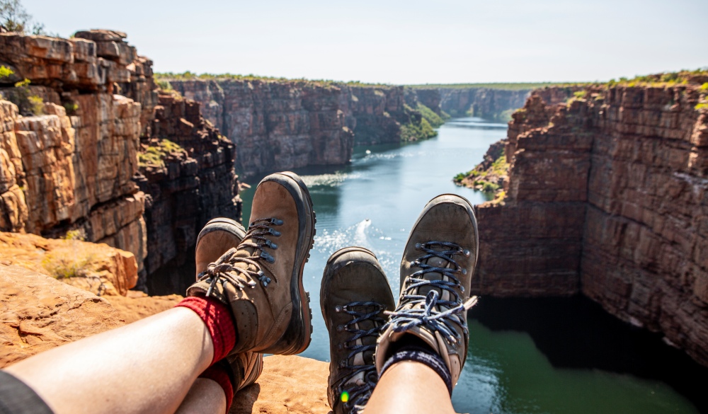 People Sitting On Rock By River Against Sky