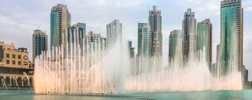 The Dubai Fountain, the world largest choreographed fountain on Burj Khalifa Lake, performs to the beat of the selected music at sunset. On background, skyscrapers of Old Town Island near Dubai Mall.