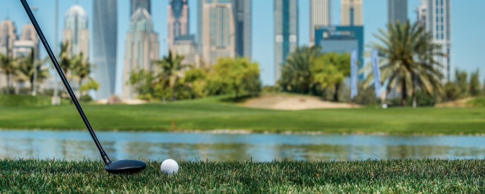 Professional Golf. Golf ball lying on the grass in front of Dubai skyscrapers. Golf courses. Close-up view of a golf ball on green grass.