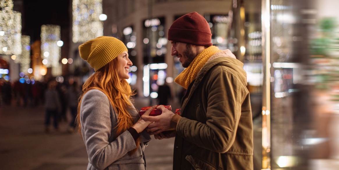 Couple in love looking at each other while holding a present.
