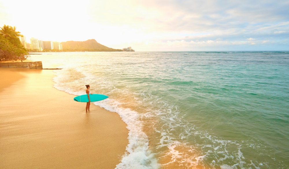 Pacific Islander woman holding surfboard on beach