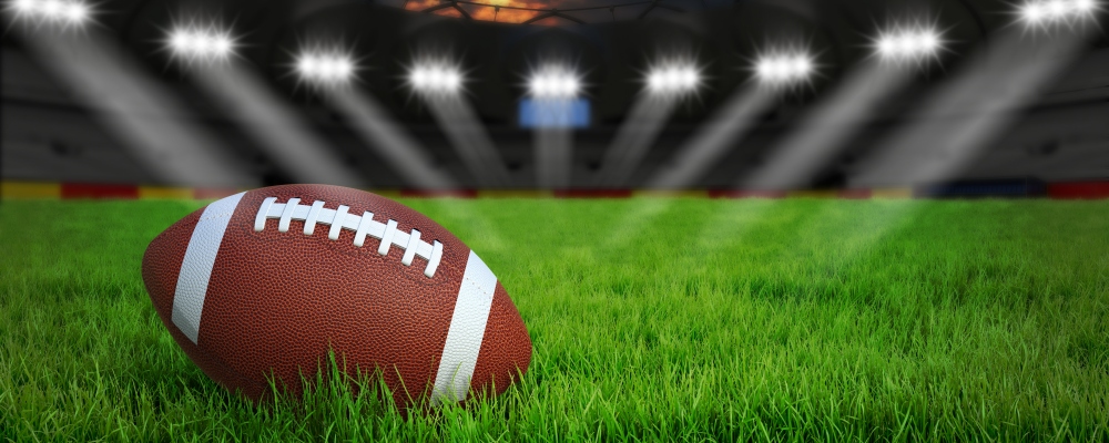American football arena with ball on green grass illumination at night, 3D rendering