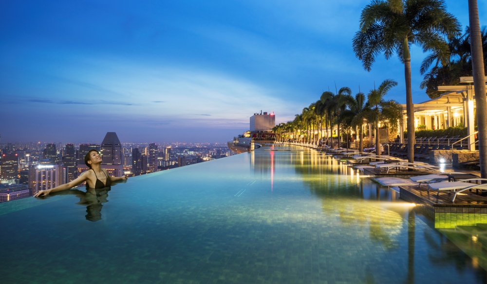 woman relaxing in infinity pool over city.