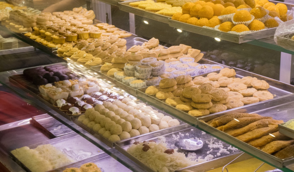 A variety of delicious Indian Bengali Sweets - gulab jamun, rasogulla, kaju barfi, kheer kadam, sandesh and laddu displayed on the street side food stall in Kolkata for sale.