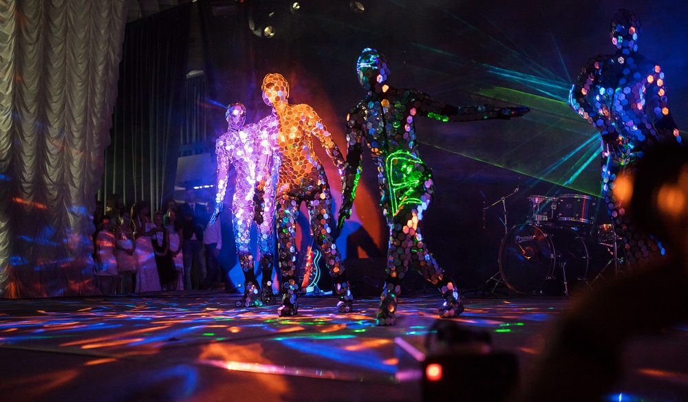 an incredible beauty of the performance of artists and dancers on stage, a fireshow with LED suits and lasers reflecting on a lot of mirror details in clothes, iridescent with all the colors; Shutterstock ID 1162497028