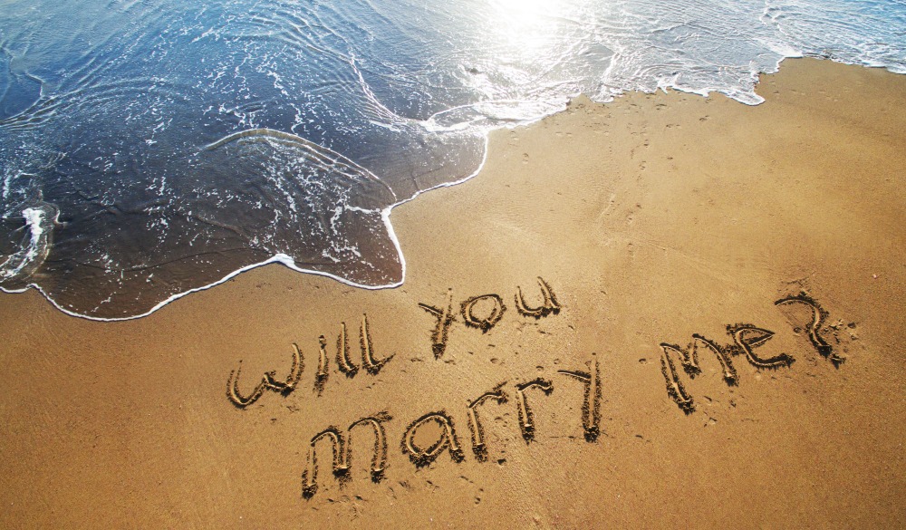 marry me written in sand on beach