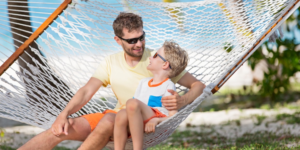 father and son, enjoying summer tropical vacation together in hammock