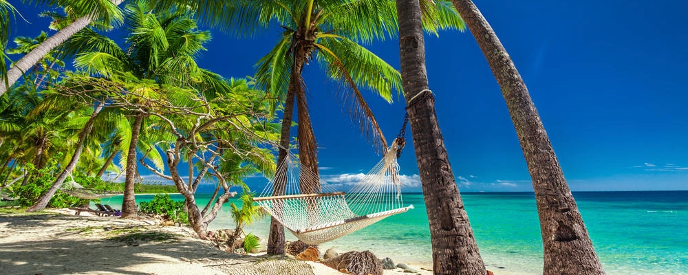 Empty hammock in the shade of palm trees on vibrant tropical Fiji Islands