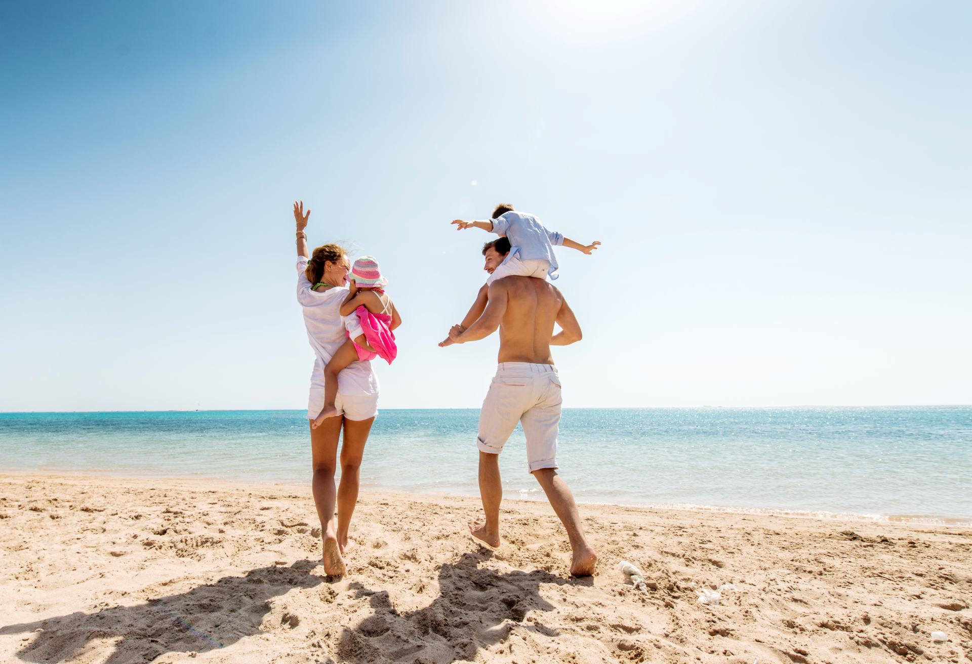 Young happy parents having fun with their children at beach.