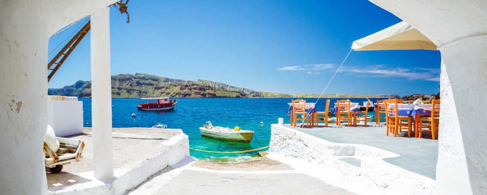 The old harbor of Ammoudi under the famous village of Oia at Santorini, Greece through a frame of an old arched building