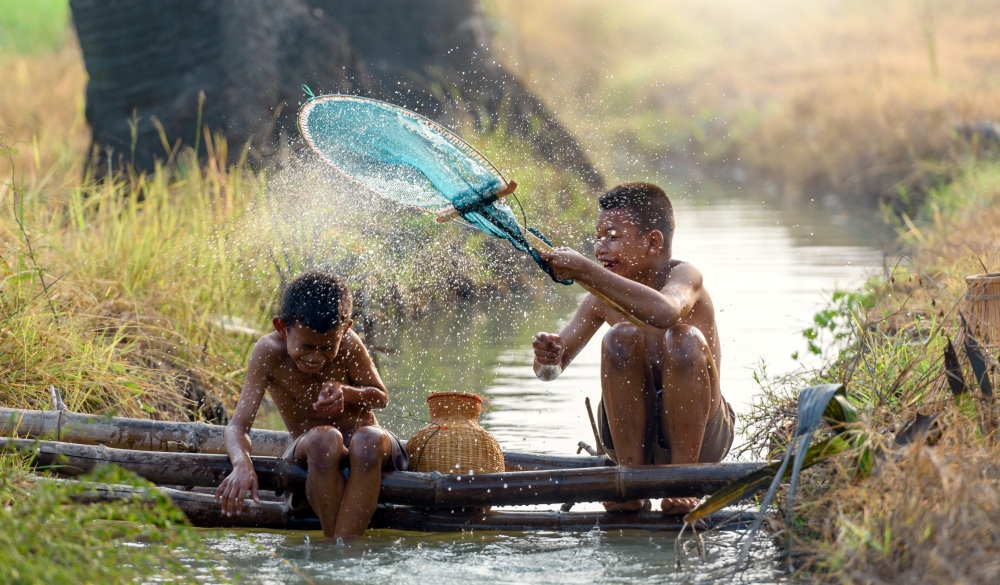 Asian children are happy and smile when they are fishing with traditional wisdom tools.