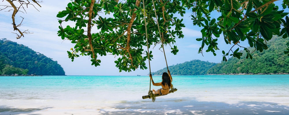 Asian girl on swing in the tropical beach island paradise of Ko Surin, Thailand