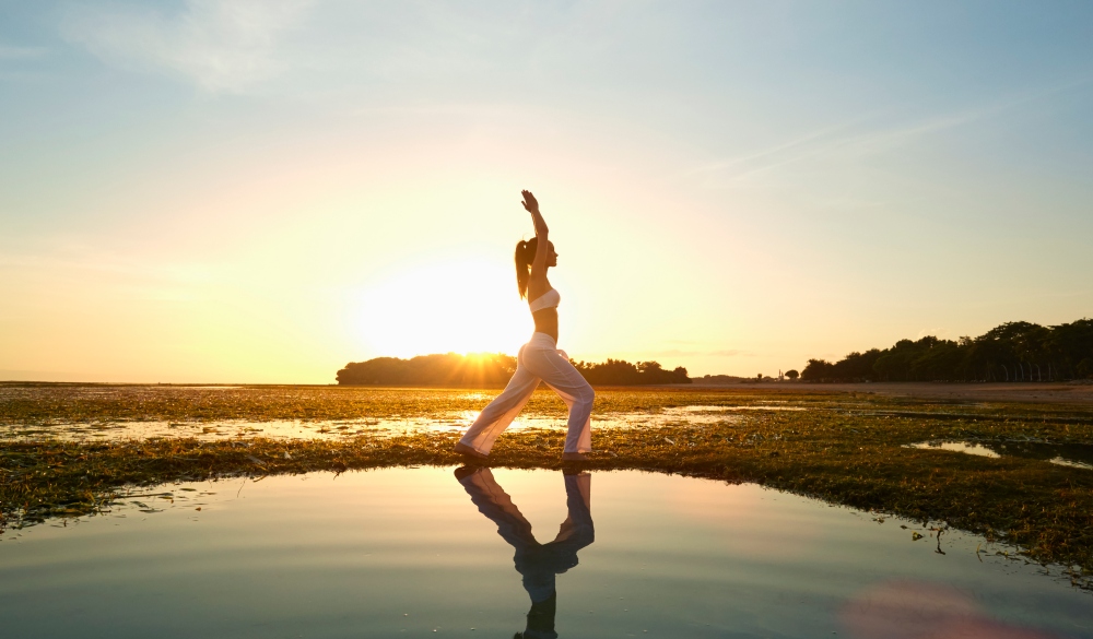 woman practicing yoga near rippling water