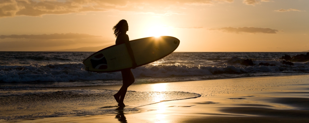 Silhouette active woman with surfboard at sunset in Hawaii enjoying beach