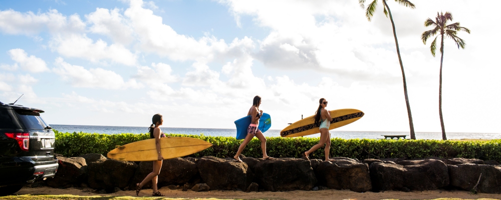 Pacific Islander surfers carrying surfboards on rock wall