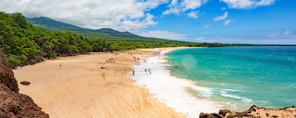 Sunbathers and swimmers on the big tropical beach at Makena State Park on Maui island in Hawaii, on a Saturday in August