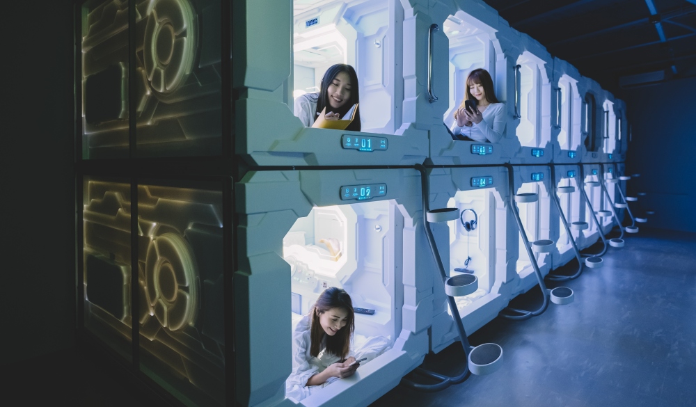 female tourist check in capsule hotel room and surfing internet and selfie on their bed with their mobile phone 