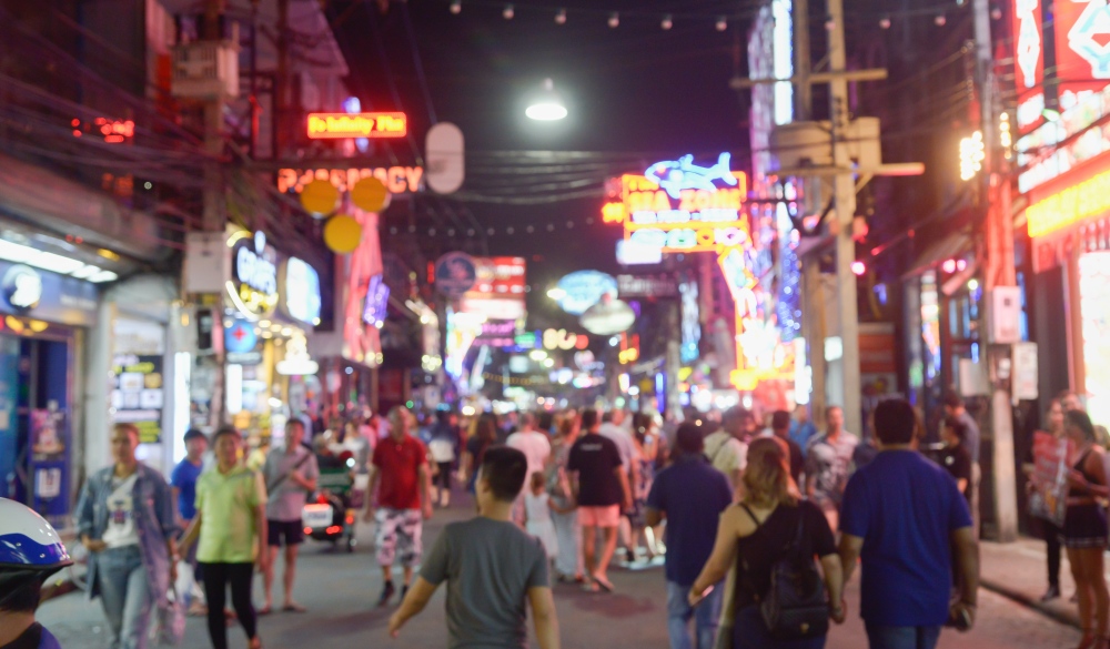  people crossing a city walking through the Walking Street in Pattaya,