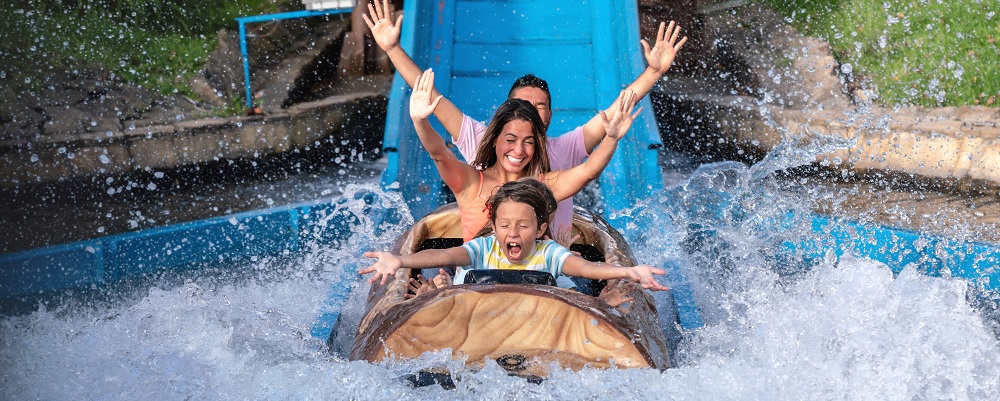 Happy family having fun in an amusement park riding on a fun water ride - lifestyle concepts