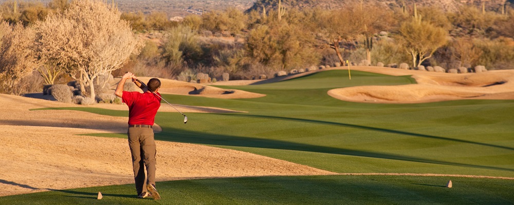 A male caucasian golfer gets ready to hit a drive on a beautiful desert golf hole. Phoenix, Arizona. The Valley of the Sun is one of the world's 