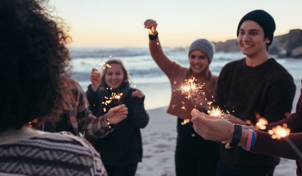 Diverse group of young people celebrating new year's day at the beach. Young people having fun with sparklers outdoors at the sea shore.; Shutterstock ID 1177933477