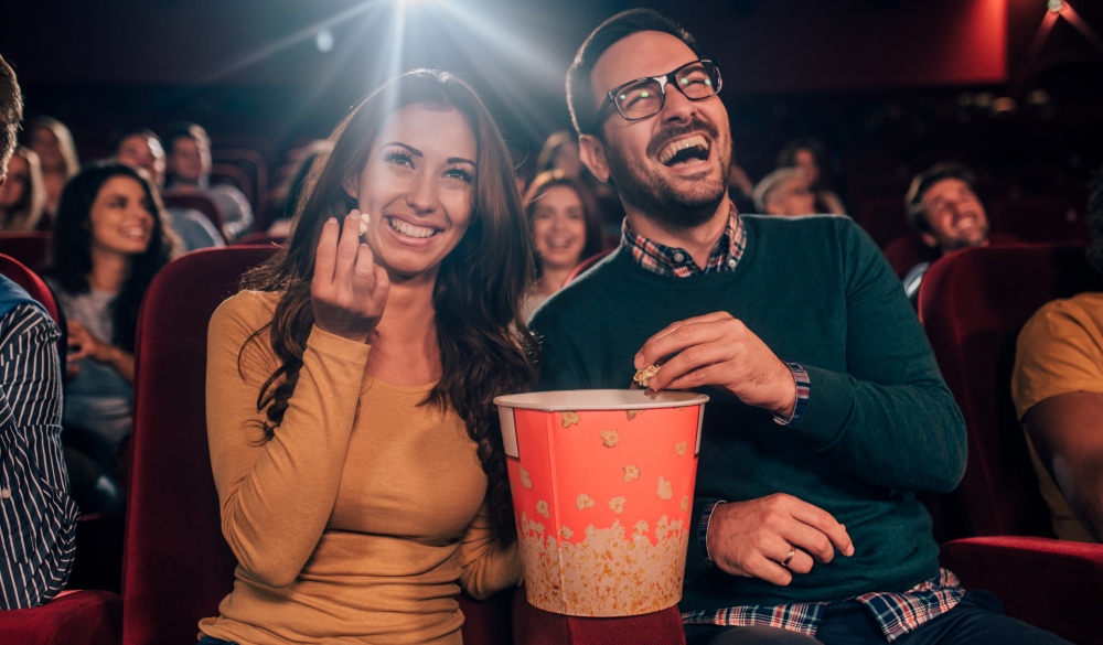 young friends eating popcorn in the cinema