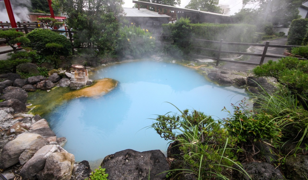 Beppu, Japan – July 2, 2008: A hot spring in Kyushu, Japan.  Due to the volcanic nature of the islands of Japan, there are a number of hot springs with a number of different properties. This particular hot spring is rich with minerals, giving it a blue appearance.  While many such hot springs are used as onsen, or hot springs baths, this particular hot spring is near the boiling point and therefore unsuitable for bathing, which is why this area is known as the 