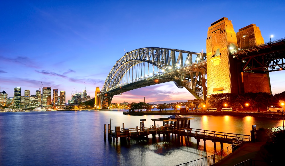 Sydney harbor bridge lights up together with the city light during dusk.