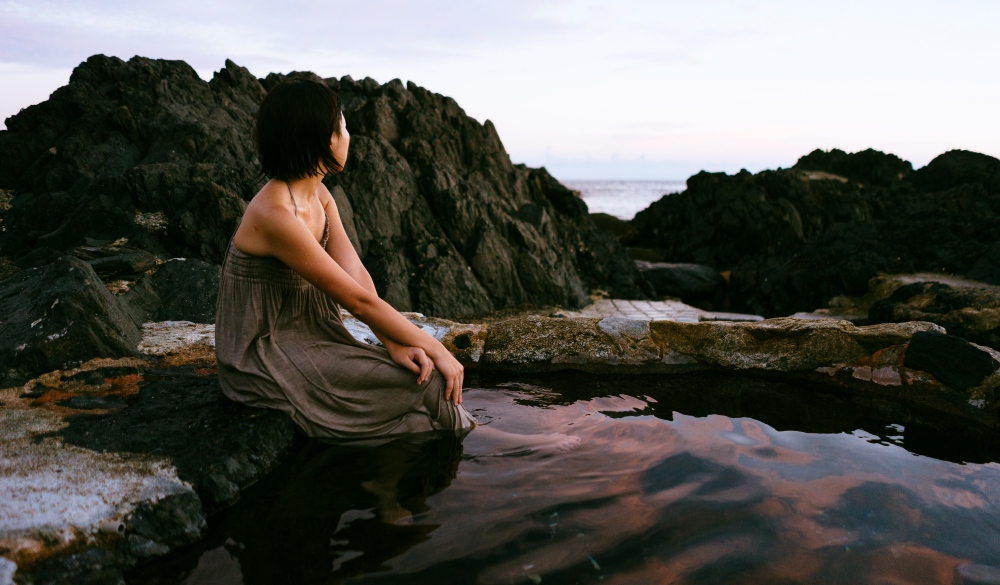 Girl relaxing in beautiful outdoor hot spring onsen in Yakushima Island, Japan by the coast