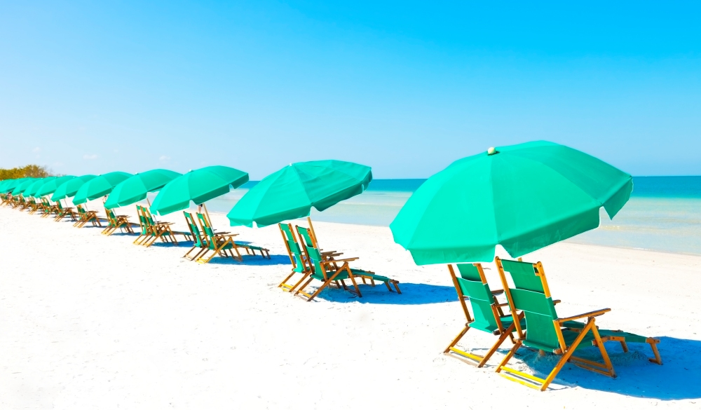 Green beach loungers and umbrellas at white sandy beach