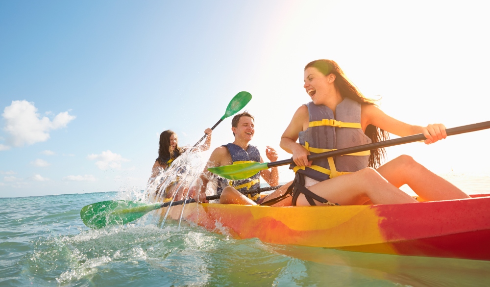 Friends rowing canoe in ocean