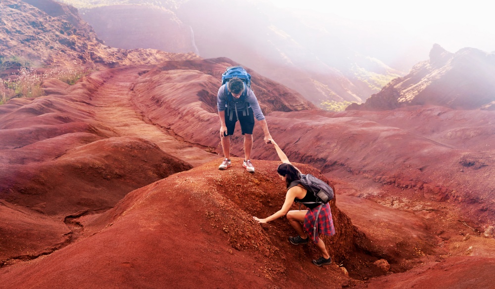 Man reaching for arm of woman hiking in canyon