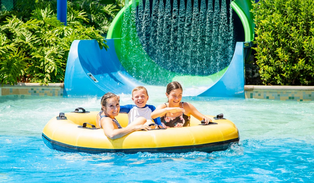 family having fun on an inflatable tube at a water park