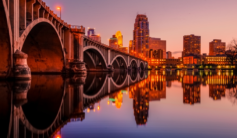 A twilight view of Minneapolis downtown  led by 3rd ave bridge or old central ave bridge. The bridge over Mississippi divides upstream St Anthony Falls and downstream Nicholet Islands. The was no major turbulence or breeze which helped me in getting a 360 degree reflection. It was the first day of spring with near 60F of this rear.