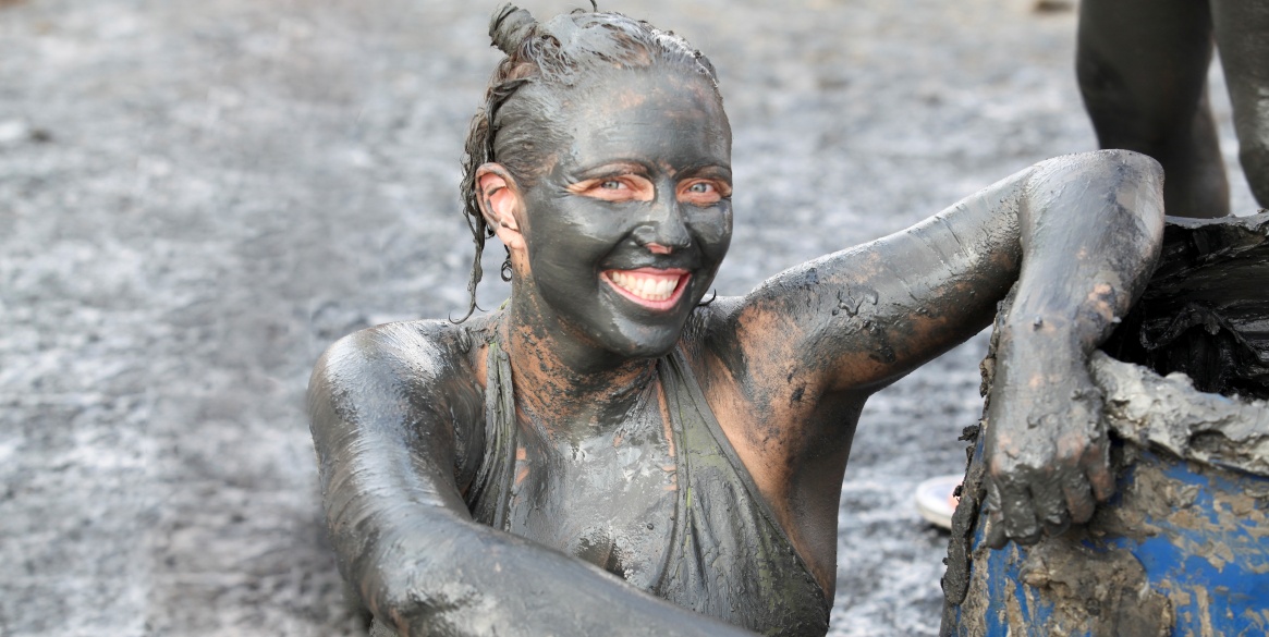 Israel, Dead Sea, tourist covers herself in therapeutic mud in order to benefit from claimed skin care properties of this mud