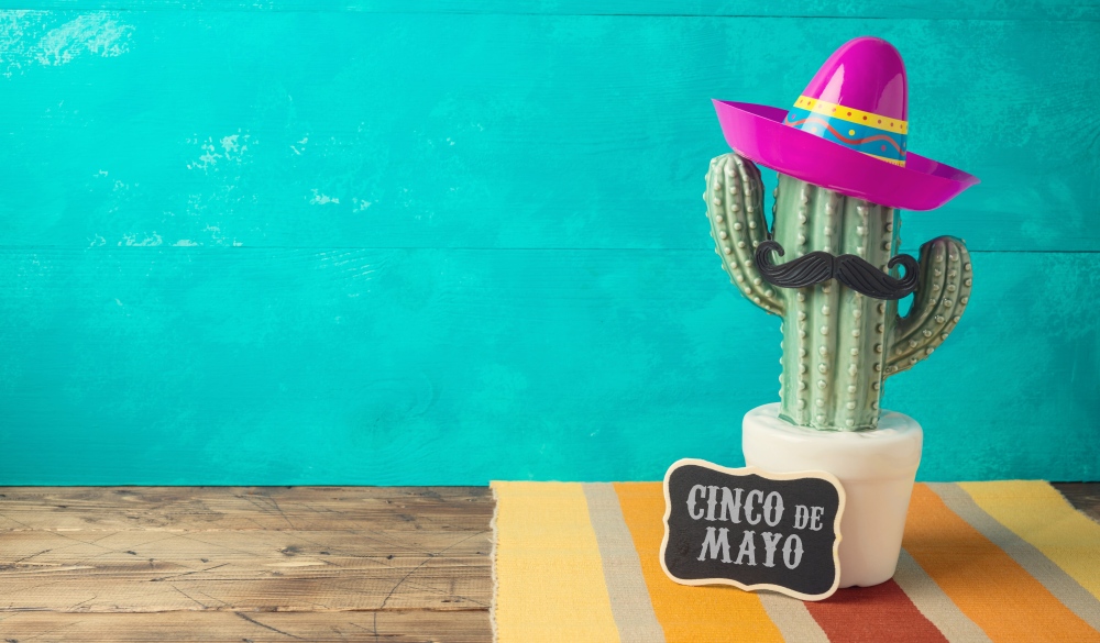 Cinco de Mayo holiday background with Mexican cactus and party sombrero hat on wooden table